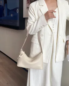 Detail view of elegant cream white leather shoulder bag featuring chic metal lock and classic style.