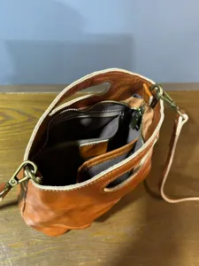Vintage leather bucket bag interior detail showing multiple pockets and metal hardware.