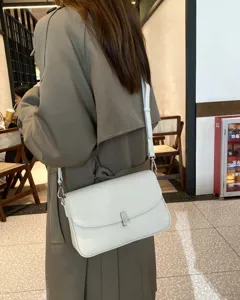 Detail shot of the white leather shoulder bag, showcasing fine leather texture and hardware.