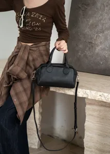 Black genuine leather Boston bag detail view, soft cowhide handbag with adjustable strap.
