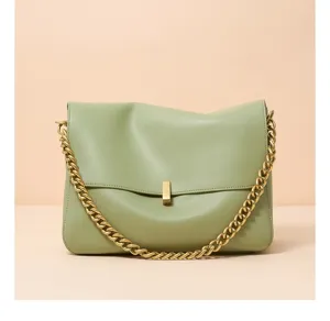 Green leather shoulder bag detail, featuring chunky gold chain and metal clasp lock.