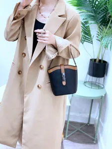 Detail shot of stylish leather color-block bucket bag with chain strap and metal lock closure.