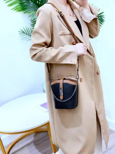 Detailed view of the trendy color-block leather bucket bag with metal chain strap.