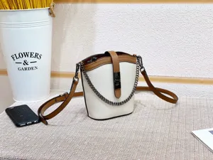 Detail shot of the color-blocking bucket bag with chain strap and elegant two-tone leather design.