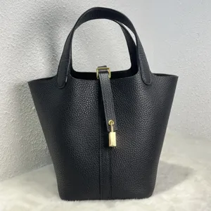 Vue détaillée du sac à main seau en cuir noir avec cadenas en métal, spacieux et élégant.