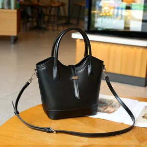 Vista detallada del elegante bolso cubo de cuero negro con textura fina y asas resistentes.