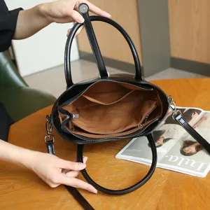 Detalle interior del bolso de cuero negro con forro de tela espacioso y compartimentos.