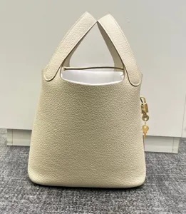 Détails du sac à main seau en cuir grainé de qualité supérieure avec cadenas doré et poignées.