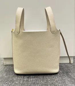 Vue détaillée du sac cabas seau en cuir véritable beige avec quincaillerie métallique de luxe.