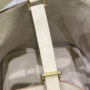 Détail intérieur de sac seau en cuir blanc montrant des finitions et quincaillerie dorée.