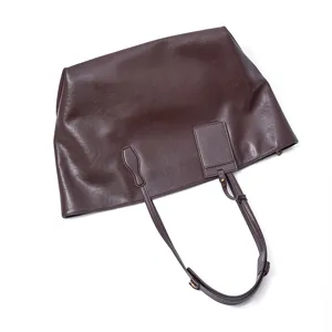 Close-up details of the dark brown genuine leather tote bag, featuring fine texture and strap.