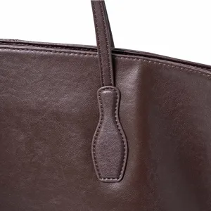Close-up detail of dark brown leather tote bag handle attachment with fine stitching craftsmanship.
