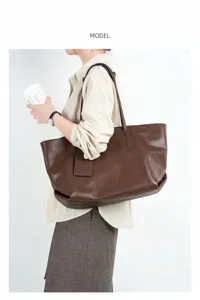 Detail view of the brown leather tote bag worn by a model, highlighting texture and capacity.
