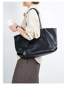 Detailed view of the black genuine leather tote bag worn on shoulder, showing soft texture.