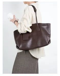 Detailed side view of a large brown leather slouchy shoulder tote bag carried by model.