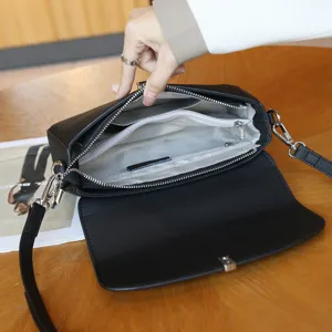 Detail view of black leather crossbody shoulder bag with multi-layer zipper interior pockets.