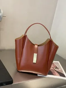 Élégant sac seau en cuir marron pour femme, sac porté épaule minimaliste avec fermoir.
