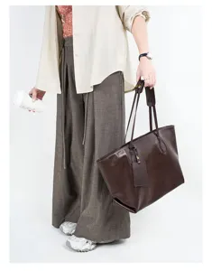 Detailed view of the dark brown leather tote bag, showing slouchy texture and slim straps.