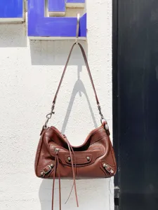 Sac bandoulière en cuir véritable marron style moto avec rivets métalliques et franges.