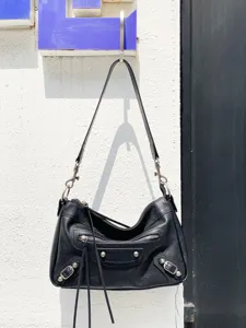 Sac porté épaule noir en cuir style moto avec clous métalliques, franges et grand format.