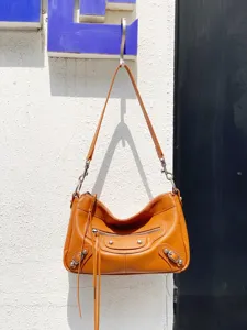 Sac à bandoulière de moto en cuir marron avec rivets métalliques, pampilles et grande capacité.