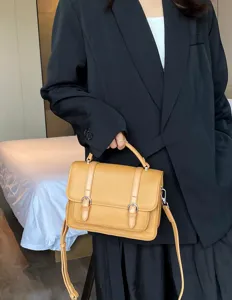 Detailed view of the stylish genuine leather messenger bag with dual buckle design and handle.