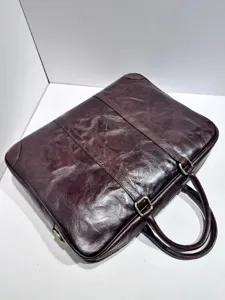 Detalle de maletín de cuero vintage, mostrando textura marrón y accesorios metálicos duraderos.
