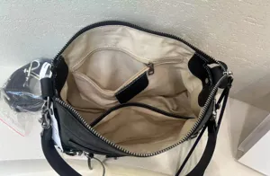 Détail intérieur de sac bandoulière hobo en cuir noir, compartiment avec poche zippée.