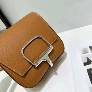 Stijlvolle bruine gestructureerde lederen schoudertas voorzien van een zilveren gesp en witte stiksels.