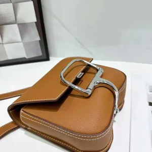 Bruine lederen crossbody tas detail, metalen gesp hardware en fijne handtas textuur.