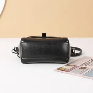 Black genuine leather cylinder shoulder bag for women, retro style crossbody handbag with metal hardware.