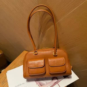Dettaglio borsa a spalla in pelle marrone, stile vintage con due tasche frontali e manici.