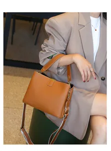 Detail shot of brown leather top handle bag with metal lock closure and adjustable strap.