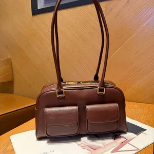 Vista dettagliata della borsa in pelle marrone con due tasche anteriori e doppi manici.