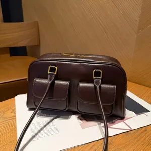 Vista di dettaglio della borsa a spalla in pelle marrone scuro con due tasche frontali e sottili.