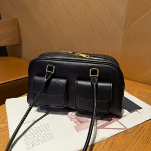 Dettaglio borsa a spalla in vera pelle nera, doppie tasche anteriori, accessori dorati.