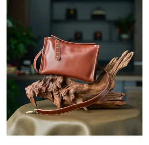 Brown leather cross-body bag detail view, showing the premium vegetable-tanned texture.