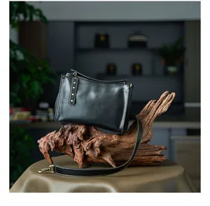 Classic black leather crossbody bag detailed view, premium vegetable tanned leather texture.