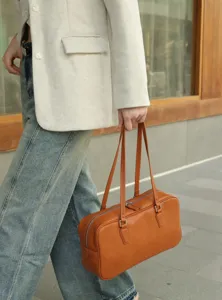 Detail view of vintage brown leather shoulder bag, elegant baguette style with double straps.