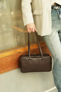Detail view of the retro brown leather shoulder bag, showing fine texture and dual straps.