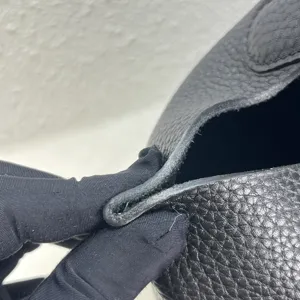 Gros plan des détails du sac seau en cuir noir, montrant des coutures et finitions de qualité.
