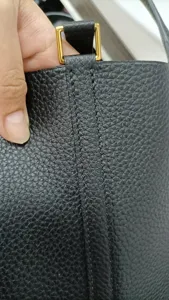 Détail de sac-seau en cuir noir fait main avec coutures fines et fermoir doré élégant.
