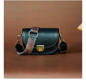 Details van de zwarte lederen zadeltas met etnische brede riem en vintage metalen beslag.