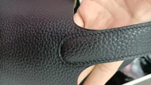 Vue rapprochée détaillée d'un sac à main en cuir noir montrant des coutures précises.