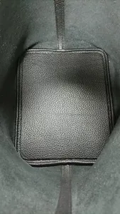 Detail interieur du sac seau en cuir montre fond durable et lignes de couture finies a la main.