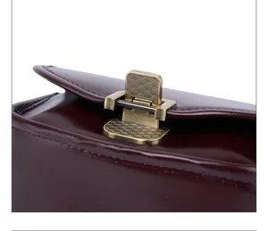 Close-up van de leren tas, wijnrood rundleer met antieke bronzen metalen slotdetails.