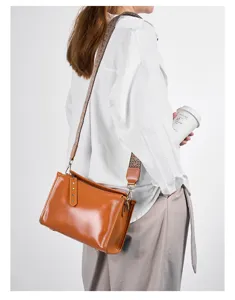 Vintage vegetable tanned leather crossbody bag with wide patterned strap for women.