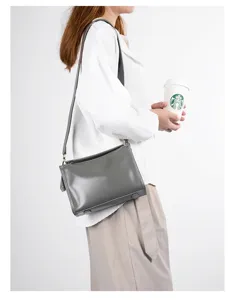 Detailed view of grey leather shoulder bag worn by model, showing premium texture and hardware.