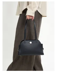 Nahaufnahme Detail der schwarzen Lederschultertasche in Hand, minimalistisches Design.
