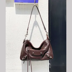 Sac bandoulière de moto en cuir marron vintage avec clous métalliques et poches zippées.
